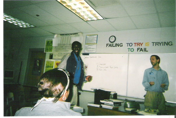 Old photo of Dr. John Underwood teaching with the phrase, "failing to try is trying to fail" behind him