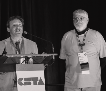Dr. J. Philip East at a CSTA conference, standing besides a podium awaiting his award. 
