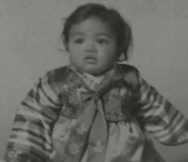 Photo of a baby with east asian features wearing a hanbok, or traditional korean dress