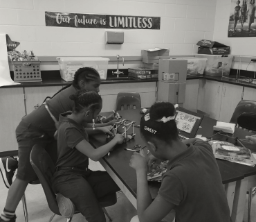 Three young African American girls building something in computer science class