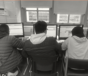 Three students, each facing a computer