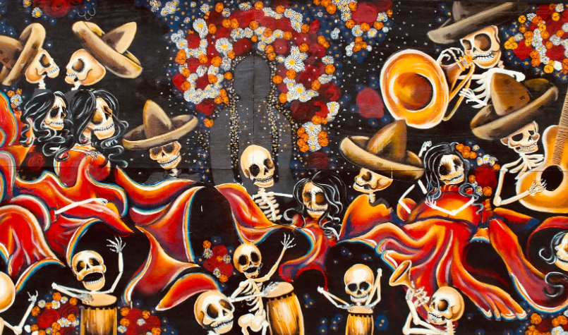 Mural depicting a celebration of skeletons in Dia de Los Muertos. Some wear sombreros, others play instruments and dance. They all have marigold clothes.