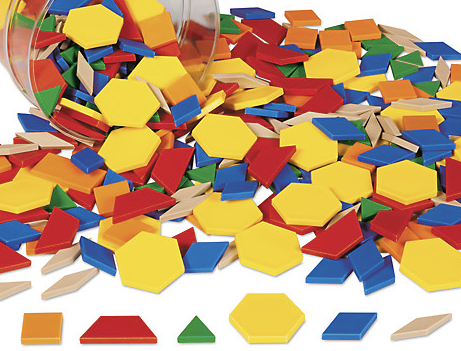 A bucket spilled over that contains wooden shapes of various colors. There are squares, trapezoids, triangles, hexagons, parallelograms, and diamonds. 