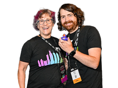 Two people wearing CSTA conference shirts post together, holding up a rubber duck between them