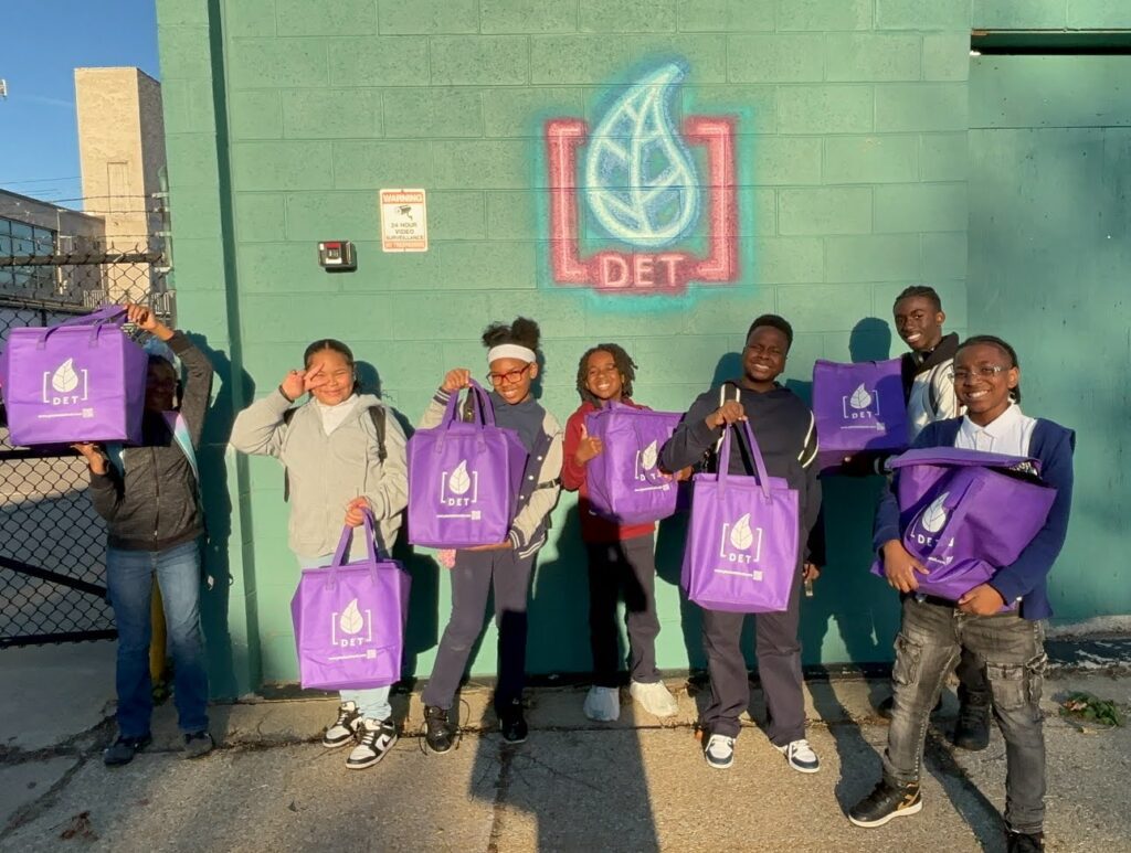 Chala's middle school students posing with Planted Detroit bags after a field trip to their facilities