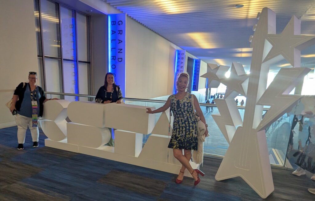 Jessa Miles and two others pose with the giant CSTA block letters at the 2025 conference.