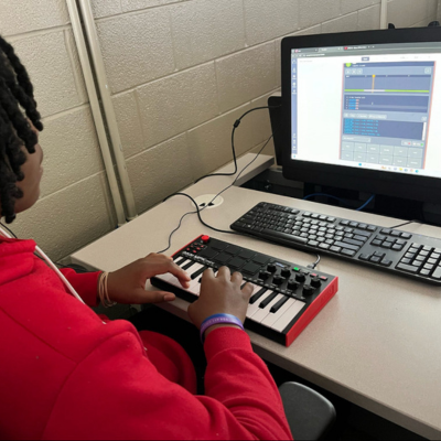 Student using a small piano keyboard to code music.